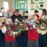 pupils presenting their christmas craft work with parents in the background