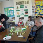 parents gathered around the table doing craft work with pupils